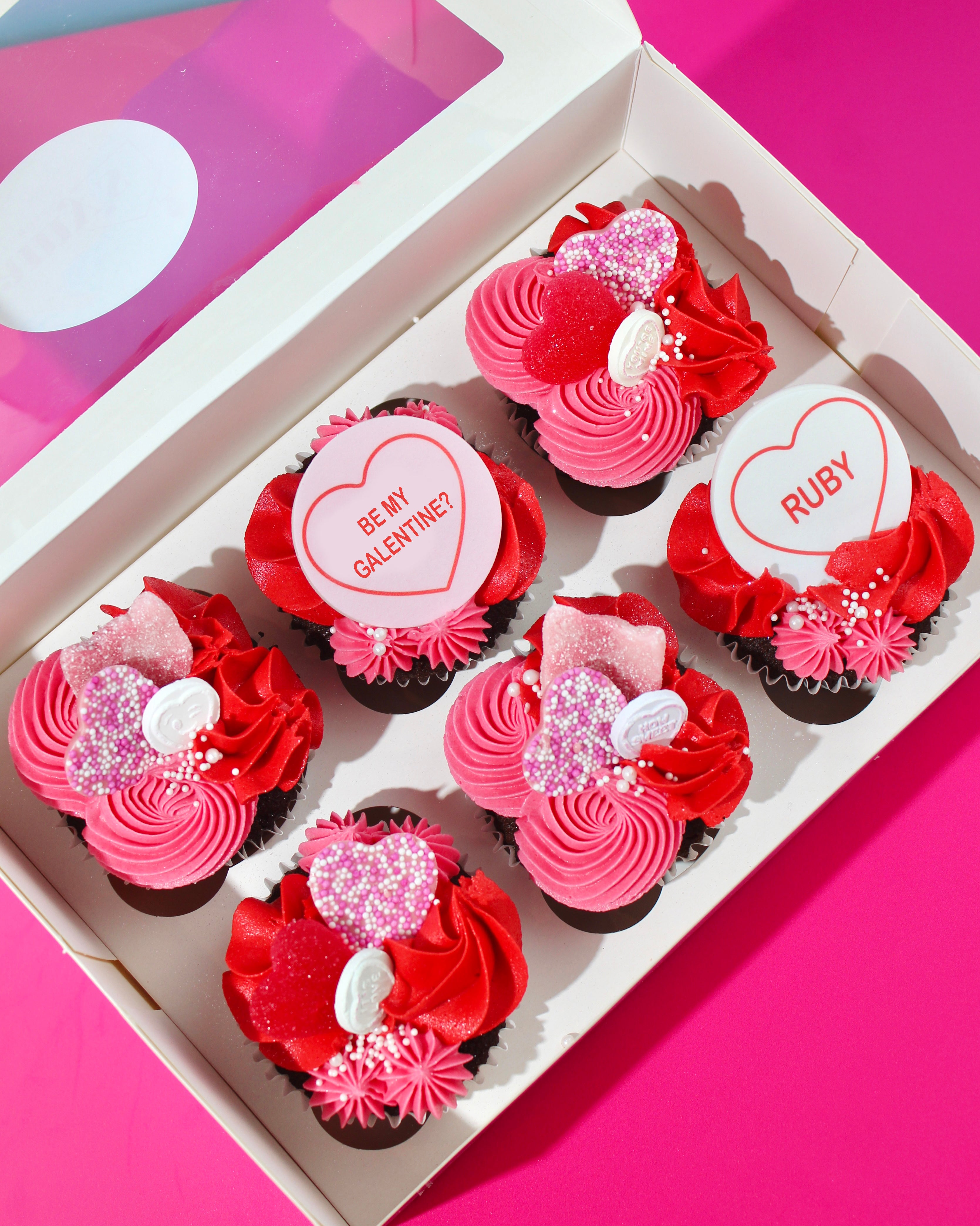 Galentine’s cupcakes in pink and red buttercream displayed in a gift box