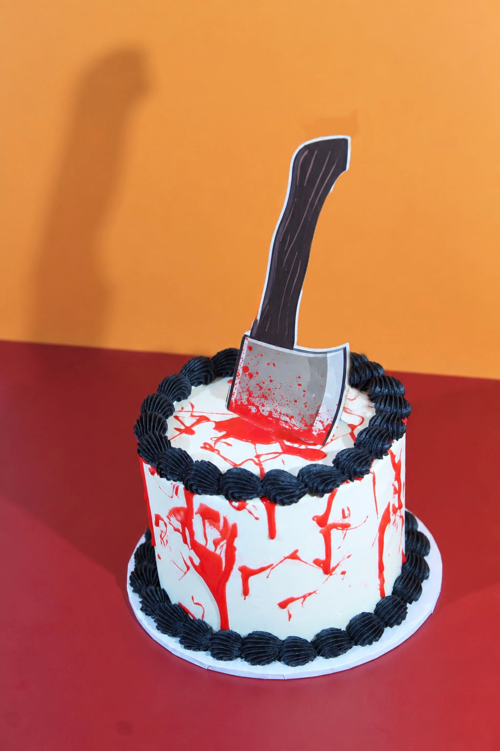Close-up of Halloween axe cake showing blood splatter detail and cleaver charm on white buttercream top