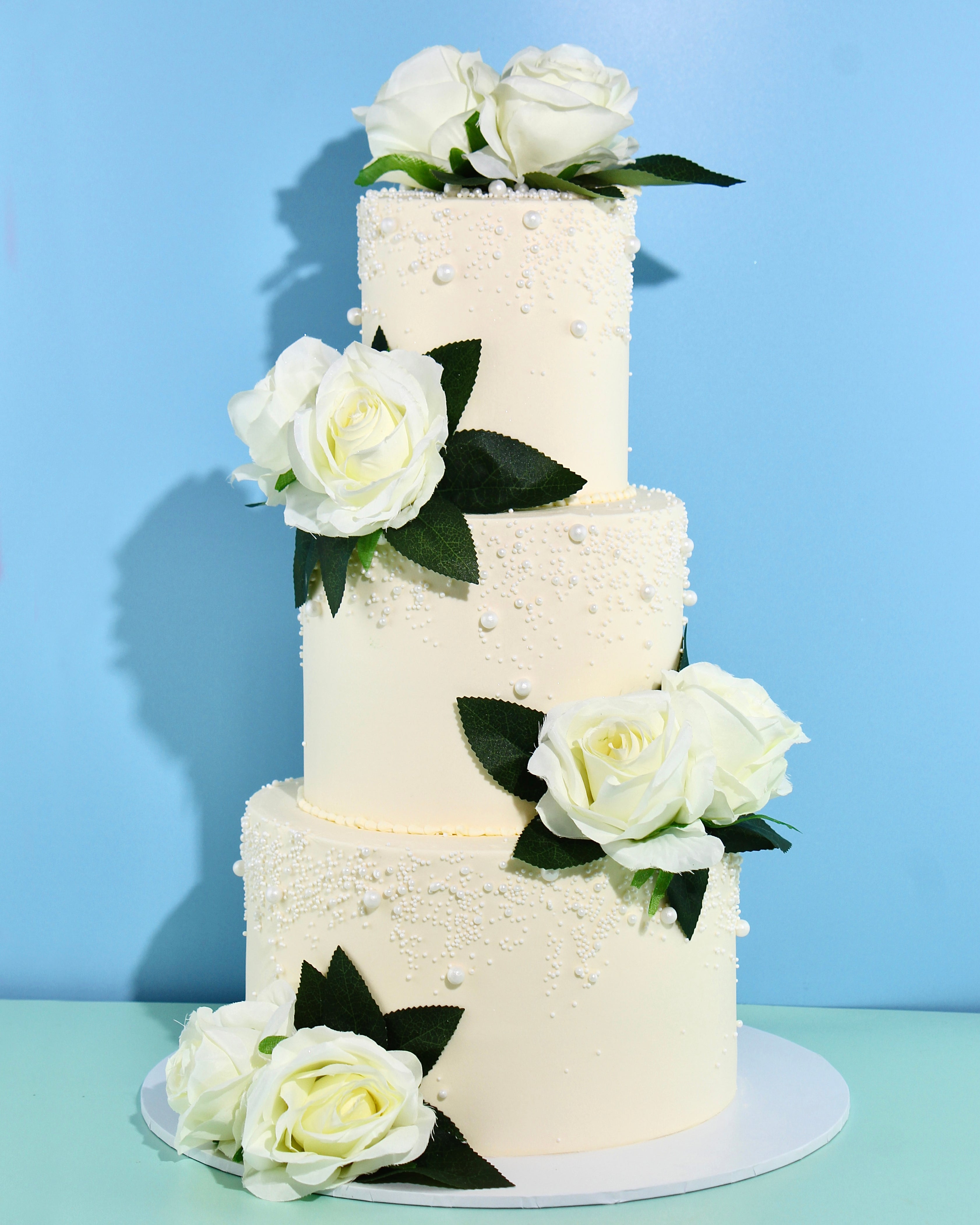 Ivory wedding cake with pearl detailing and white rose floral accents